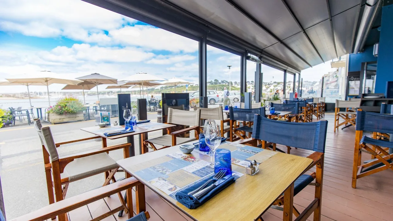 Les tables du Quai des Saveurs à Camaret-sur-Mer, près de la baie vitrée ouverte sur la terrasse et le port.